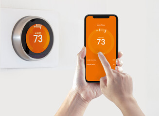 A person using a smart phone application warming up the room temperature with a wireless smart thermostat on a white background. - obrazy, fototapety, plakaty
