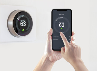 A person using a smart phone application saving energy with a wireless smart thermostat on a white...