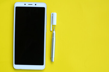  stylus pen and cell phone on yellow background