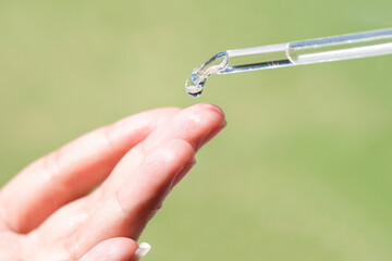 hands of a beautiful woman Dropping serum collagen moisturizer of face soft light background....