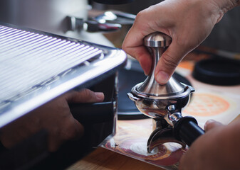 Fototapeta na wymiar Close-up view of on hands barista presses ground coffee using tamper.