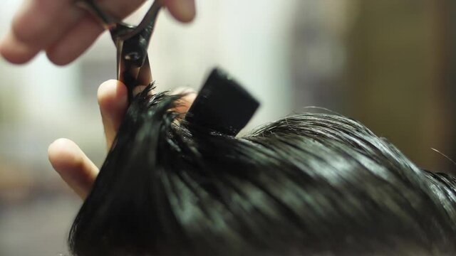 barber cutting client hair with scissors slow motion