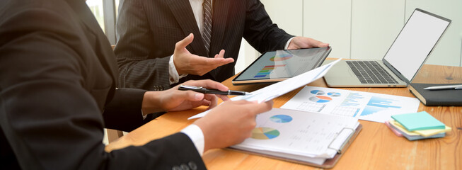 Business partner consulting on their collaboration with digital device and document file in meeting room