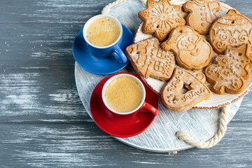 Homemade gingerbread cookies on tray with cup of coffee on grunge gray  wooden background. Christmas and New Year celebration background.  Close up of home baked cookies with icing.