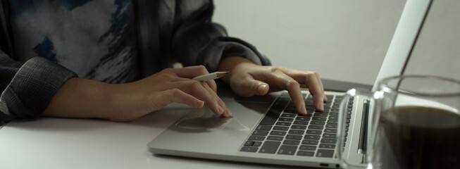 Fototapeta na wymiar Female freelancer writing an e-mail on laptop while sitting at portable workspace
