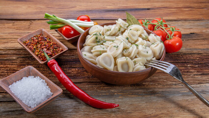 homemade dumplings with sour cream and dill on a wooden vintage table with fresh tomatoes, onions and spices