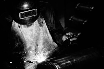 welder working welding process on metals with welding mask and individual protection equipment