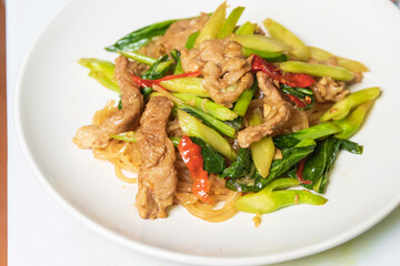 Stir-fried rice stick noodles in sweet soy sauce with pork, chili and chinese broccoli in white plate.