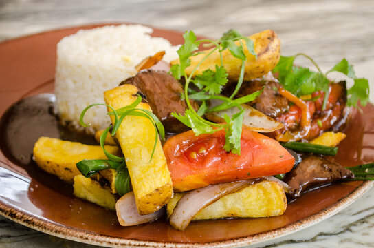 Lomo Saltado - A popular Chifa (Peruvian - Chinese) stir fry dish combining marinated beef sirloin, onions, tomatoes and french fries, served with white rice