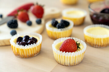 Mini cheesecake with blueberry, blackberry and strawberry ready to be served on wooden table