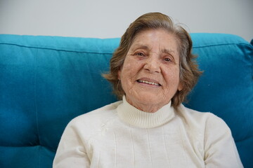 Sorriso de uma senhora da terceira idade. Mulher idosa sentada no sofa exibindo sua felicidade. 