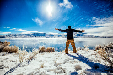 Male person looking at a lake enjoying the view, Snow and Winter