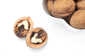 Walnuts in a white bowl and half of walnut next to the bowl. Clean surface. Top view | above, heart shaped nut. Isolated. Copy space for text editing, white background. Close up