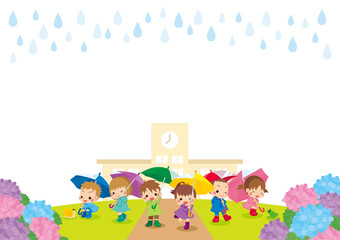 雨の日にアジサイの咲く学校の前でレインコートを着て傘を差している子どもたち