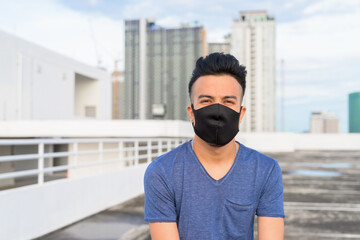 Face of young multi ethnic man with mask at rooftop of the building outdoors