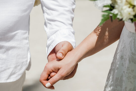 Newlyweds at the wedding romantic couple holding hands during destination wedding marriage matrimonial ceremony on the sandy beach in Dominican republic, Punta Cana. Family, love, unity concept.  