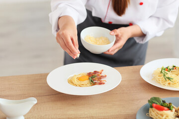 Obraz na płótnie Canvas Female chef cooking tasty dish in kitchen, closeup