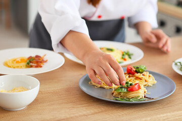 Female chef cooking tasty dish in kitchen, closeup