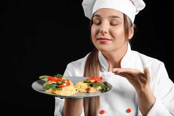Young female chef with tasty dish on dark background
