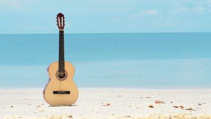 An acoustic guitar under summer sky on a beautiful sandy beach