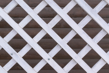White wooden lattice for backdrop. Background of brown boards. Structure of rhombus.