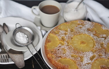 Sponge cake with pineapple on a dark wooden table.Home cooking.