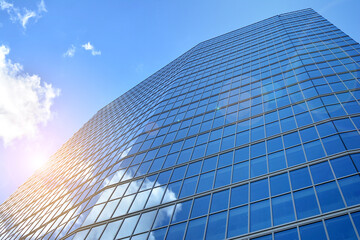 Fototapeta na wymiar Facade texture of a glass mirrored office building. Fragment of the facade. Bottom view of modern skyscrapers in business district in evening light at sunset with lens flare filter effect.