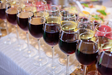 Rows of glasses filled with red and white wine, close-up. Wine at holiday celebration. Banquet service. Catering.
