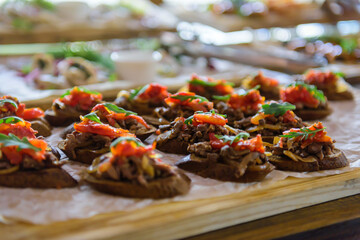 Small sandwiches on buffet table, selective focus. Cold appetizers, close-up. Catering for banquets and weddings.