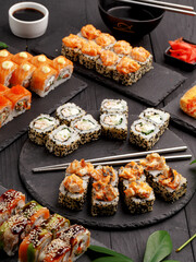 Sushi rolls on colored plates on a black background. A look from above.