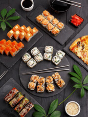 Sushi rolls on colored plates on a black background. A look from above.