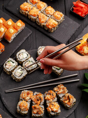 Sushi rolls on colored plates on a black background. A look from above.