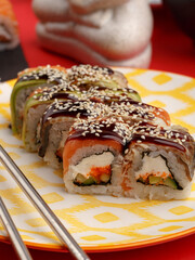 Sushi rolls on colored plates on a red background. A look from above.