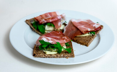 sandwich with ham, cheese and parsley on black bread