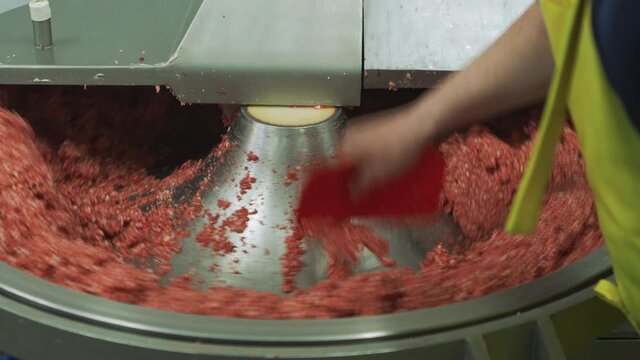 Worker food factory working with meat chopper machine, mixing meat and spices for making hot dogs and sausages in a food factory. Close up. Part of sausage production. 4k
