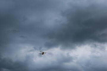 Flying drone in storm background. Uav drone with high resolution camera take aerial photo of storm cloud sky before raining. White small drone flying in the sky. Copy space for text.