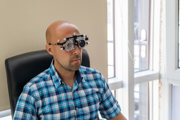 vision measurement by optometrist at clinic, young man as patient