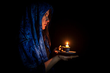 Sad young woman with candle and blue headscarf