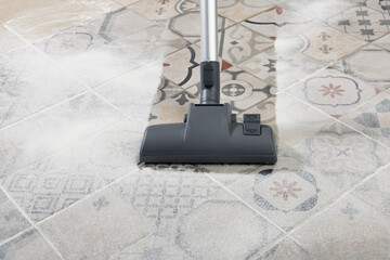 cleaning and removing dust with modern vacuum cleaner in kitchen room.
