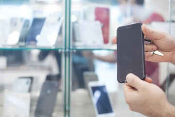 Man showing a smartphone in electronics store.