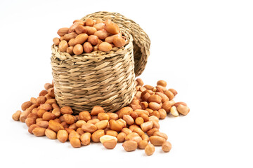 Isolated image, Close up peanuts in wicker basket on white background. Some peanuts spread around basket. Fresh peanuts seed without shell.