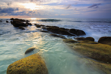 Amazing twilight Sunset seascape with sea wave hitting the green moss