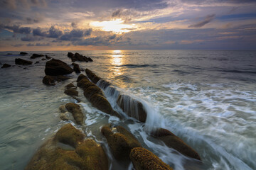 Amazing twilight Sunset seascape with sea wave hitting the green moss