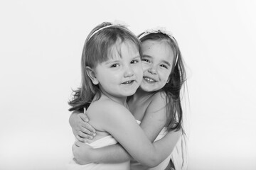 two little happy girls smiling on white background. Portrait of children hugging. The concept of relationships in the family, friends, sisters, couple in love. Copy space
