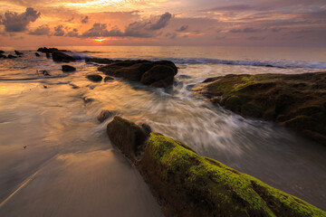 Amazing twilight Sunset seascape with sea wave hitting the green moss
