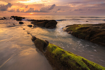 Amazing twilight Sunset seascape with sea wave hitting the green moss