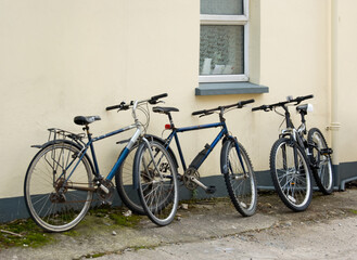 Fototapeta na wymiar Three old rusty black bicycles leaning against a cream wall