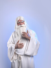A grey-haired, severe sorcerer in a white cassock is doing sorcery and magic against a light...
