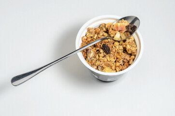 Muesli in a round jar on a white background with sprinkled crumbs. Diet breakfast with milk or yogurt. Selective focus.