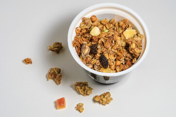 Muesli in a round jar on a white background with sprinkled crumbs. Diet breakfast with milk or yogurt. Selective focus.